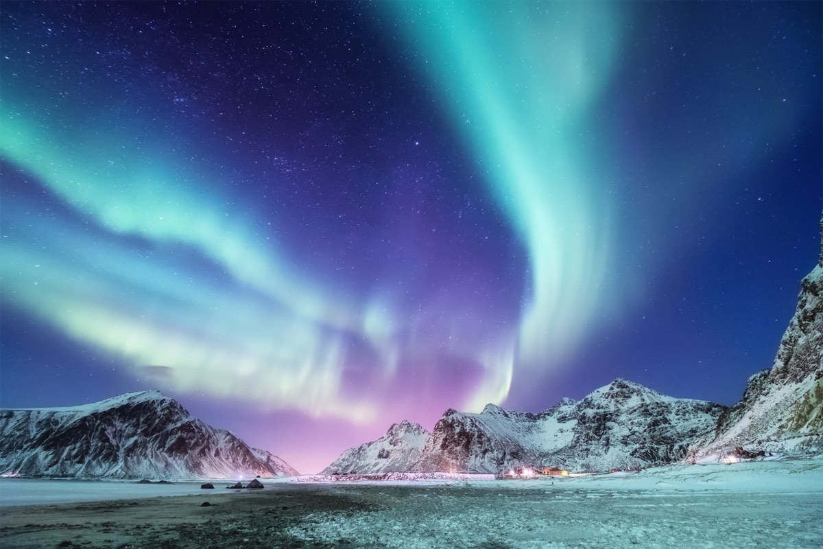 blue and purple colored aurora borealis over a snowed covered mountain landscape