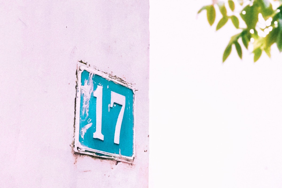 Number 17 metal plate with teal background on pink wall