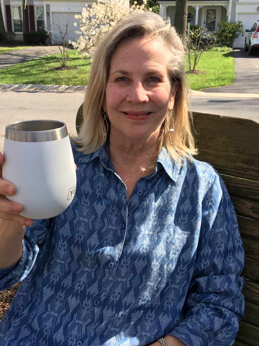 Jane toasting with a Yeti wine cup with neighborhood homes in background